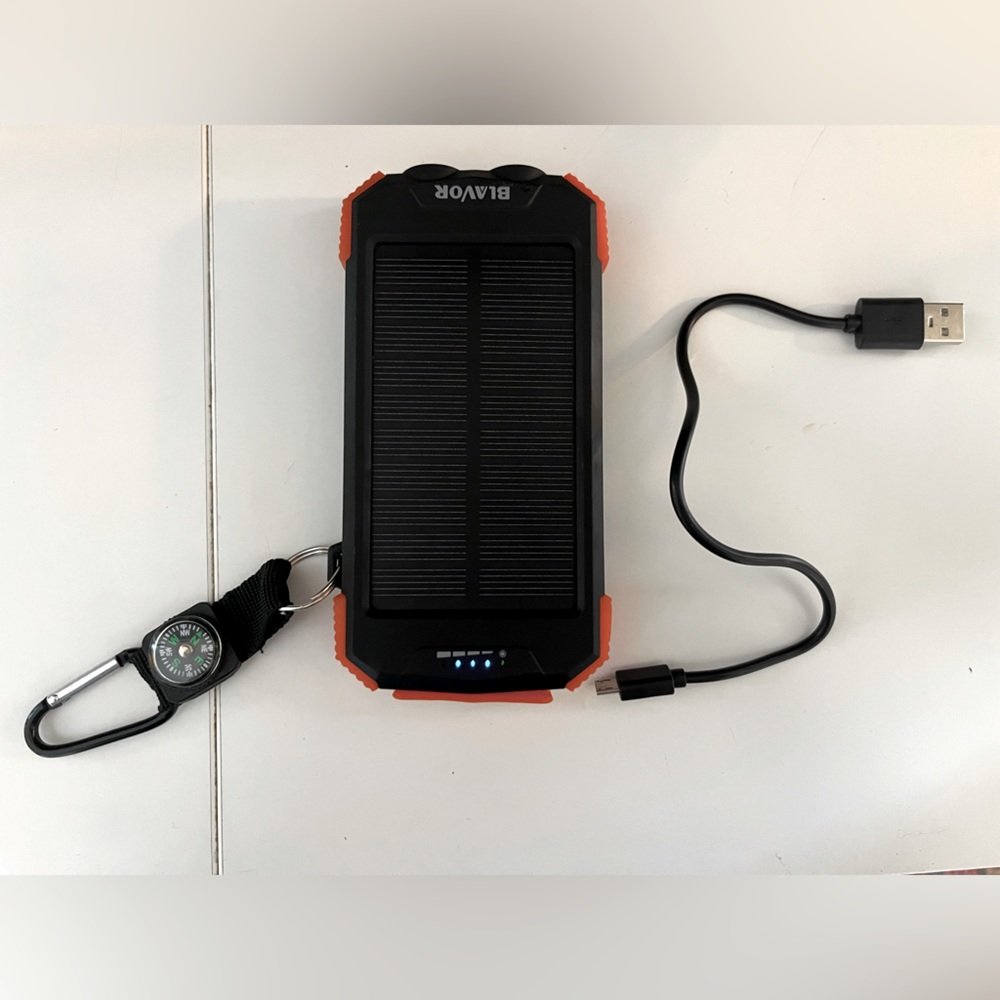 Solar powered charging bank with flashlight and charging cord.